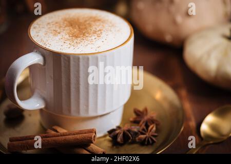 Tazza di spezia di zucca tardiva o di eggnog con bastoncini di cannella, anice stellato di zucche e noce moscata in un ambiente rustico e vintage Foto Stock