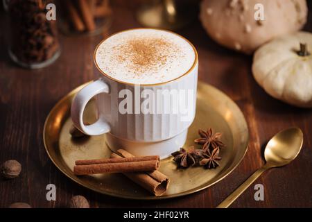 Tazza di spezia di zucca tardiva o di eggnog con bastoncini di cannella, anice stellato di zucche e noce moscata in un ambiente rustico e vintage Foto Stock
