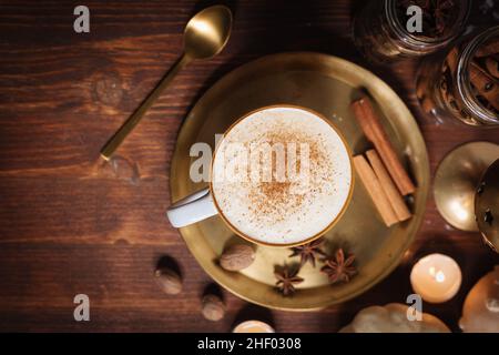 Tazza di spezia di zucca tardiva o di eggnog con bastoncini di cannella, anice stellato di zucche e noce moscata in un ambiente rustico e vintage Foto Stock