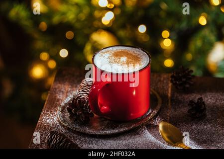 Tazza di spezia di zucca in ritardo in una moody rustica e l'atmosfera di Natale vintage e le luci di Natale e l'albero in sfondo sfocato Foto Stock