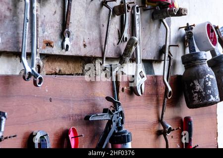 vari attrezzi meccanici per un'officina per il servizio auto e la riparazione di auto si appende sulla parete di legno Foto Stock