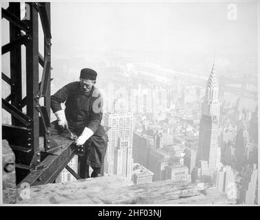 Fotografia di un operaio edile che imbullonano le travi sul quadro dell'Empire state Building. Sullo sfondo (a destra) si trova il Chrysler Building. Foto Stock