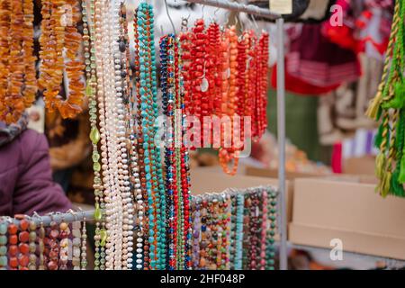 Gioielli realizzati in pietre naturali sul mercato delle pulci o sul mercato dei souvenir. Collane vecchie e nuove in vendita, gioielli fantasia in negozio mercato delle pulci. Messa a fuoco selettiva Foto Stock