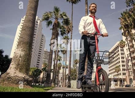 Giro in giro. Felice avvocato giro e-scooter sul marciapiede. Guida scooter elettrico Foto Stock