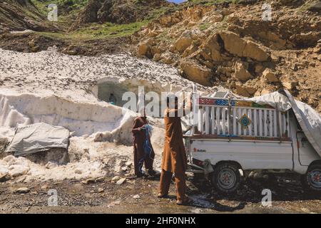 Gilgit, Pakistan - 08 giugno 2018: Le persone pakistane raccolgono neve e caricano l'auto in montagna Foto Stock