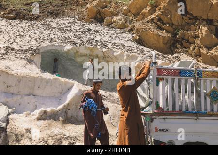 Gilgit, Pakistan - 08 giugno 2018: Le persone pakistane raccolgono neve e caricano l'auto in montagna Foto Stock