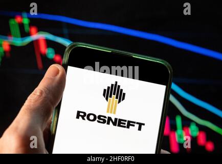 In questa foto raffigura la multinazionale russa del petrolio e del gas, il logo Rosneft visto su uno smartphone con un grafico di indice di borsa economica sullo sfondo. Foto Stock