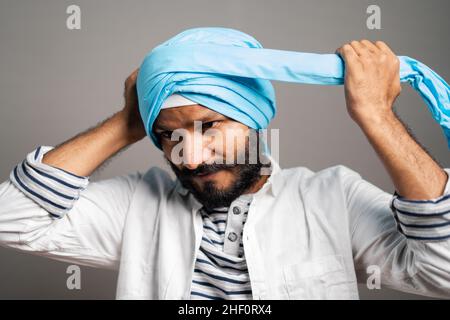 uomo indiano sikh indossando tretitional turban su sfondo grigio - concetto di religione custume e identità. Foto Stock