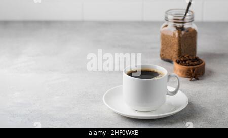 Caffè istantaneo nero in una tazza bianca su sfondo grigio. Spazio di copia. Foto Stock