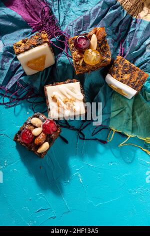 Ricco dolce budino natalizio carico di frutta secca, noci e spezie su un vibrante sfondo turchese orientale Foto Stock