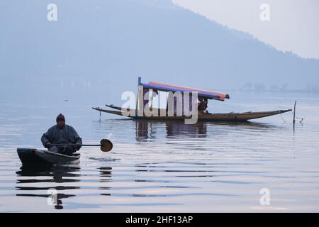 Srinagar, Kashmir, India. 13th Jan 2022. Un uomo si infila sulla sua barca durante una fredda giornata invernale al lago dal a Srinagar. La valle del Kashmir è attualmente sotto la morsa del periodo invernale di 40 giorni più impegnativa, noto come 'chilla-i-Kalan', iniziato il 21 dicembre. (Credit Image: © Adel Abbas/ZUMA Press Wire) Foto Stock
