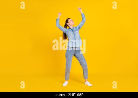 Foto a tutta lunghezza di bella funky giovane donna vestito jeans camicia salto sorridente isolato colore sfondo giallo Foto Stock