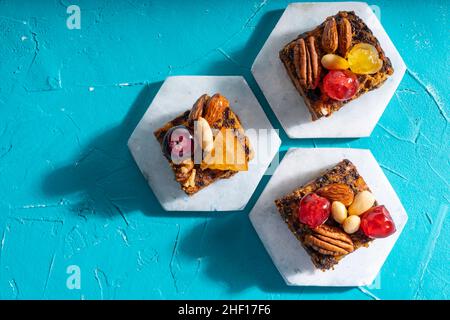 Ricco dolce budino natalizio carico di frutta secca, noci e spezie su un vibrante sfondo turchese orientale Foto Stock