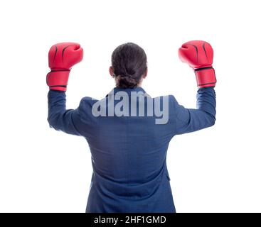 Uomo d'affari con vista posteriore in tuta con guanti da boxe rossi che alzano le mani celebrando la vittoria in una lotta. Confronto tra uffici, successo della pe aziendale Foto Stock