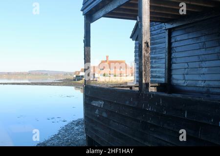 Vista dal Bosham Quay dell'antico magazzino Raptackle in primo piano e edificio residenziale sullo sfondo. Foto Stock