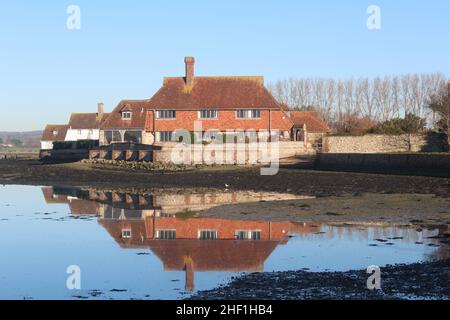 Riflesso della proprietà residenziale lato porto in Area of Outstanding Natural Beauty, Bosham, West Sussex. Un cielo blu chiaro in un giorno d'inverno. Foto Stock