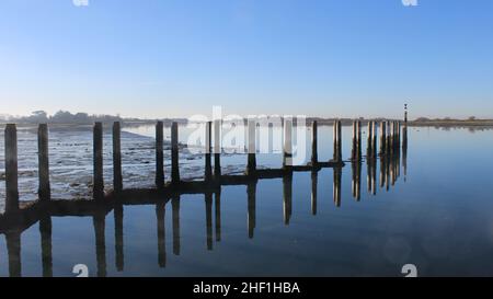 I posti di ormeggio a Bosham Quay si riflettevano nell'acqua. Foto Stock