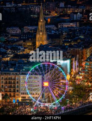 San Sebastián de noche en navigades con la noria funcionando, se puede ver tambien la catedral del buen pastor iluminada. Foto Stock