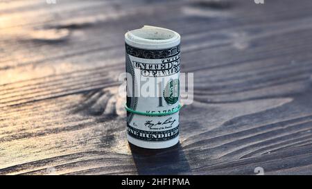 Rotolo di mille dollari 1000 dollari in cento fatture del dollaro isolato su sfondo di legno Foto Stock