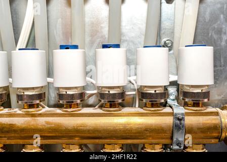 Nuovo collettore in ottone per riscaldamento a pavimento con attuatore termoelettrico chiuso e aperto. Foto Stock