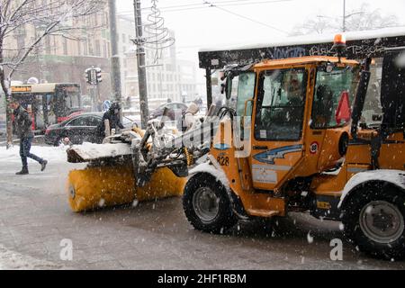 Belgrado, Serbia - 11 gennaio 2022: Rimozione e rimozione di una leggera polvere di neve dalla strada della città con spazzaneve marciapiede, manutenzione invernale Foto Stock