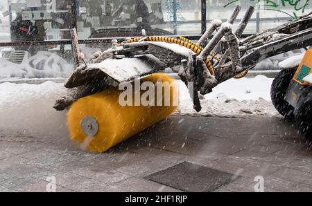 Macchina per lo sgombero della neve con spazzatrice che rimuove la polvere dalla passerella laterale durante la manutenzione invernale della città, dettaglio Foto Stock