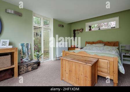 Clare, Suffolk - 27 Aprile 2018: Cottage camera da letto all'interno di una casa ristrutturata decorata semplicemente con pareti dipinte di verde e letto matrimoniale. Foto Stock