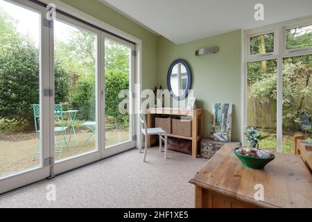 Clare, Suffolk - 27 Aprile 2018: Camera da letto al piano terra in cottage di campagna inglese con tavolo da toeletta e porte patio Foto Stock