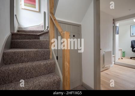 Clare, Suffolk - 27 Aprile 2018: Corridoio cottage con scale che conducono al primo piano adiacente al corridoio che a sua volta conduce alla zona di studio Foto Stock