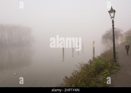 Un solo pareggiatore circondato da fitta nebbia su un sentiero desertato sulle rive del Tamigi, Strand-on-the-Green, Chiswick, Londra, Inghilterra, REGNO UNITO Foto Stock