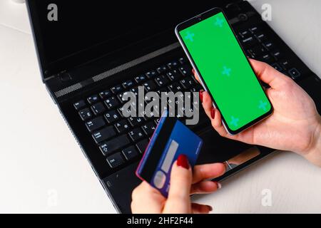 Immagine ravvicinata delle mani della donna utilizzando lo smartphone bianco schermo verde mockup e tenendo la carta di credito Foto Stock