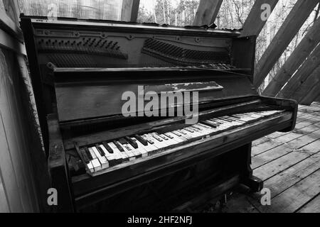 Vecchio piano vintage rotto. Nero distrutto e dimenticato pianoforte in luogo abbandonato. Foto in bianco e nero. Foto Stock