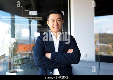 Ritratto di successo imprenditore maschio boss asiatico allegro felice sorridente e gioire in ufficio moderno da grande finestra Foto Stock