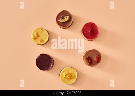 Dolci di goji, lampone, mirtillo, limone e banana crudi vegan su sfondo arancione pastello Foto Stock