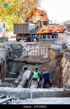 Samara, Russia - 16 ottobre 2021: Lavori di costruzione di grandi tubi di ferro nella trincea scavata. Sostituzione dei tubi di riscaldamento in città Foto Stock