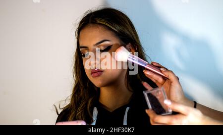 Adolescente guardando il suo telefono, mentre il suo amico sta facendo il suo trucco Foto Stock