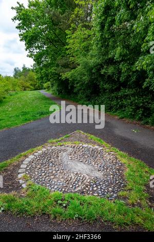 Foto del pavimento di un Heron fatto da pietre di ciottoli ad un incrocio nel sentiero a Sankey Valley Park, Cheshire, Inghilterra Foto Stock