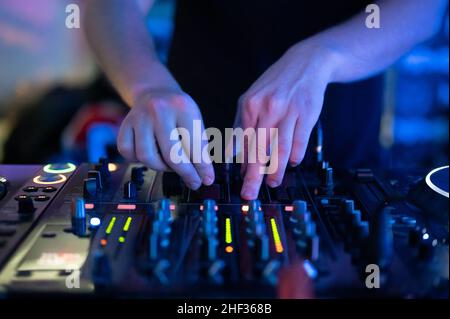 Primo piano Vista frontale delle mani del DJ che controllano un tavolo musicale in un night club. Foto di alta qualità Foto Stock