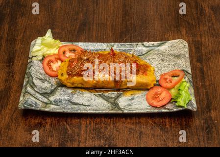 Il tamale è un alimento di origine precolombiana, di culture mesoamericane, generalmente preparato a base di pasta di mais o di riso farcito con carni, verdure, Foto Stock