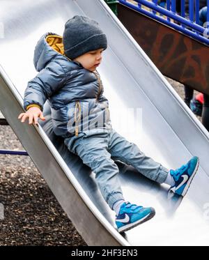 Ragazzo di due anni sul parco giochi della città slidboard Foto Stock