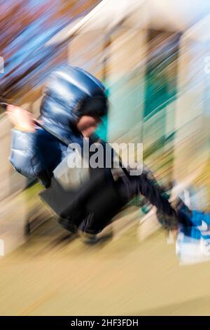 Blur - Pan - foto d'azione di un ragazzo di due anni che oscilla sul parco cittadino; Corinthian Gardens; Philadelphia; Pennsylvania; USA Foto Stock