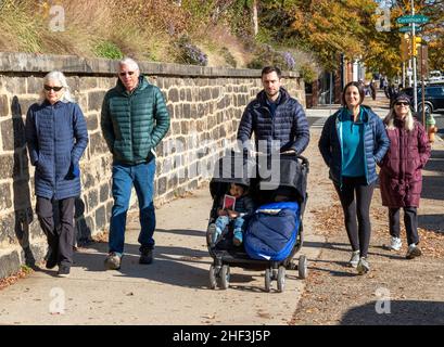 Famiglia con due bambini piccoli che vengono spinti in un passeggino lungo un marciapiede della città Foto Stock