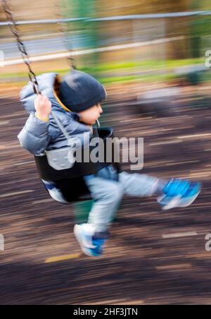 Blur - Pan - foto d'azione di un ragazzo di due anni che oscilla sul parco cittadino; Corinthian Gardens; Philadelphia; Pennsylvania; USA Foto Stock