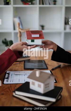 Gli agenti stanno dando casa al cliente dopo aver firmato il contratto d'accordo presso l'ufficio dell'agenzia. Accordo e concetto immobiliare. Foto Stock