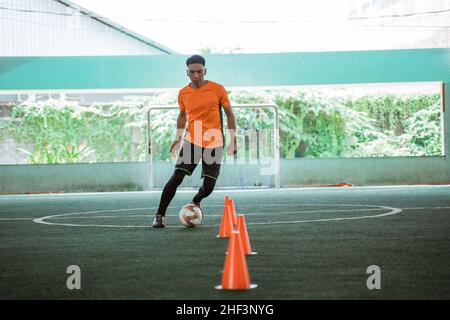 un giocatore di futsal maschile che pratica il dribbling su un cortile interno Foto Stock