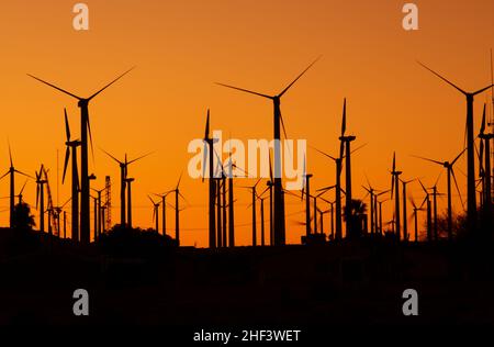 Grande impianto di energia eolica durante il tramonto panoramico. Turbine eoliche silhouettes. Foto Stock