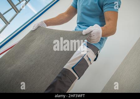 Lavoratore che prepara pezzo di Wall Vinyl Wallpaper da applicare ai suoi clienti Appartamento Wall. Foto Stock