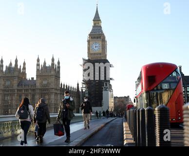 Londra, Gran Bretagna. 13th Jan 2022. Le persone che indossano maschere camminano sul Westminster Bridge a Londra, in Gran Bretagna, il 13 gennaio 2022. Da lunedì, il periodo di autoisolamento per le persone completamente vaccinate in Inghilterra che si sono verificate positive per COVID-19 sarà ridotto da sette giorni a cinque giorni interi, il Segretario della Sanità britannico Sajid Javid ha annunciato giovedì. Credit: Li Ying/Xinhua/Alamy Live News Foto Stock