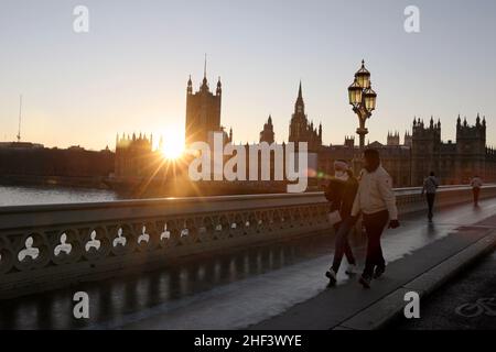 Londra, Gran Bretagna. 13th Jan 2022. Le persone che indossano maschere camminano sul Westminster Bridge a Londra, in Gran Bretagna, il 13 gennaio 2022. Da lunedì, il periodo di autoisolamento per le persone completamente vaccinate in Inghilterra che si sono verificate positive per COVID-19 sarà ridotto da sette giorni a cinque giorni interi, il Segretario della Sanità britannico Sajid Javid ha annunciato giovedì. Credit: Li Ying/Xinhua/Alamy Live News Foto Stock