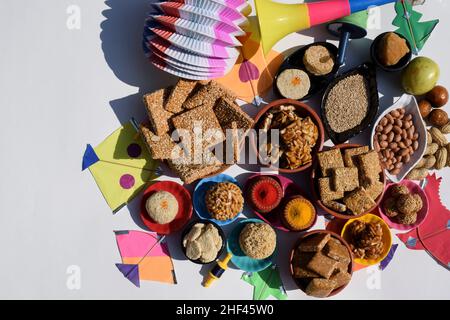 Carta da parati Makar sankranti con piatti speciali del festival Sankranti serviti e consumati come Peanut chikki, tilgul laddu, til baati, frutta bor, arachidi, Foto Stock